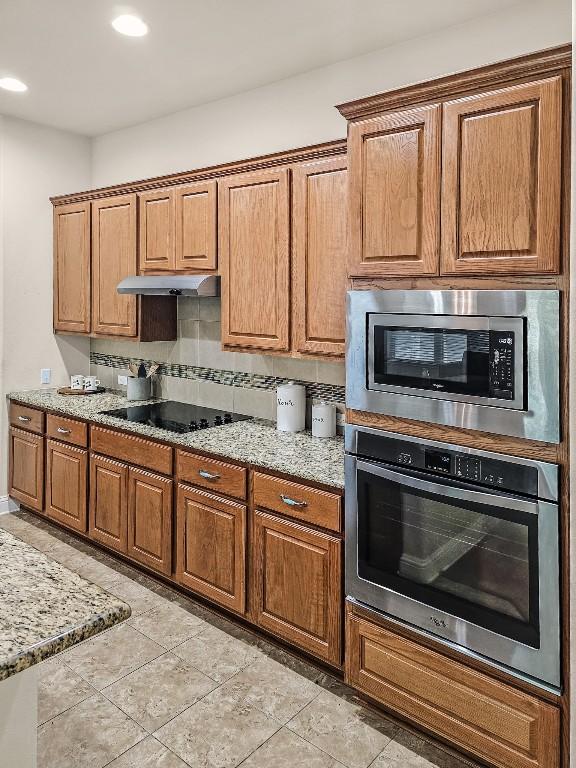 10601 Twisted Elm Dr, Austin, TX 78726 - kitchen with stainless steel appliances, brown cabinetry, light stone countertops, decorative backsplash, and recessed lighting