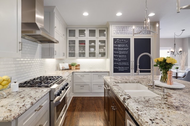 10204 Treasure Island Dr, Austin, TX 78730 - kitchen with wall chimney range hood, stainless steel stove, a chandelier, dark wood-style flooring, and white cabinets
