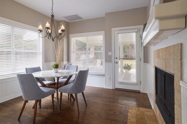 10204 Treasure Island Dr, Austin, TX 78730 - dining room with wainscoting, a chandelier, a tiled fireplace, wood finished floors, and a decorative wall