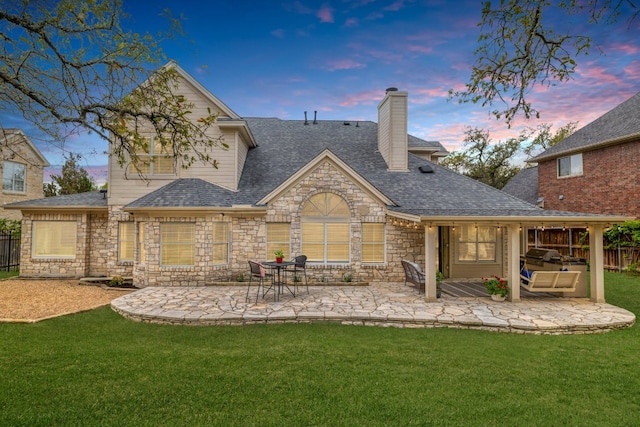 10204 Treasure Island Dr, Austin, TX 78730 - back of property with a patio, stone siding, a chimney, and a shingled roof