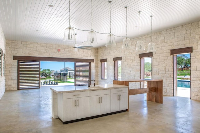 8408 Bouvreuil Dr, Austin, TX 78738 - kitchen with finished concrete floors, white cabinets, pendant lighting, and a kitchen island with sink