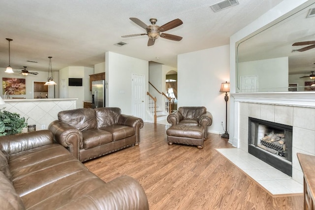 2435 Candle Ridge Trl, Georgetown, TX 78626 - living area with visible vents, a tiled fireplace, a ceiling fan, and wood finished floors