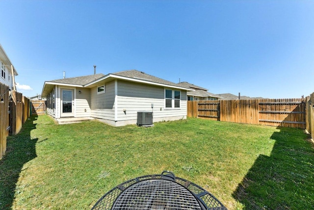 rear view of property featuring a yard, central AC unit, and a fenced backyard