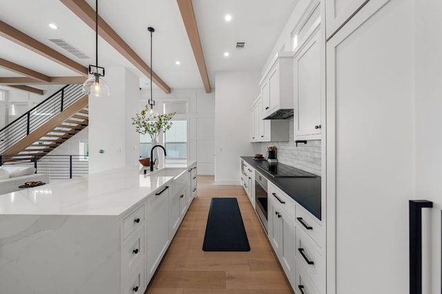 13408 Galleria Cir, Austin, TX 78738 - kitchen with light wood-style flooring, tasteful backsplash, white cabinets, oven, and a sink