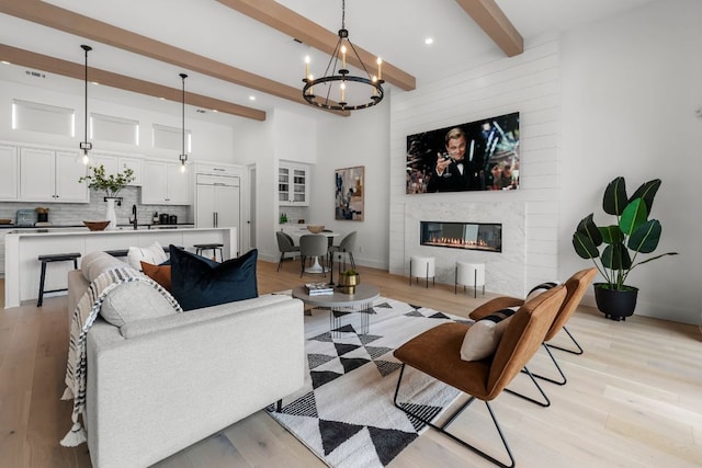 13408 Galleria Cir, Austin, TX 78738 - living room featuring beam ceiling, light wood-style flooring, a chandelier, a fireplace, and recessed lighting