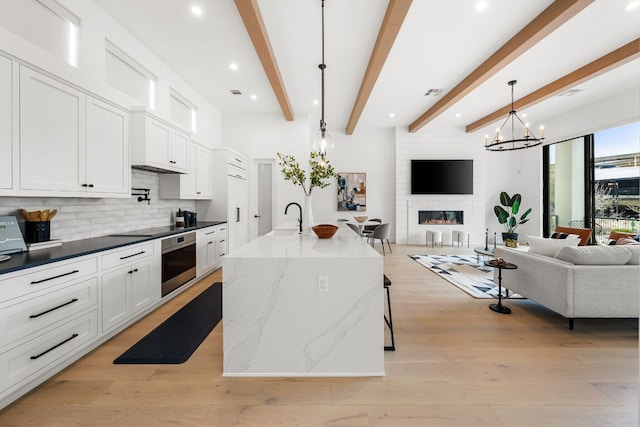 13408 Galleria Cir, Austin, TX 78738 - kitchen featuring open floor plan, oven, tasteful backsplash, light wood-type flooring, and beam ceiling