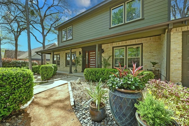 rear view of property featuring covered porch and brick siding