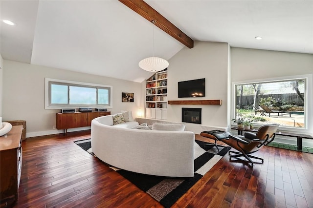 living room with healthy amount of natural light, dark wood finished floors, a glass covered fireplace, built in shelves, and recessed lighting