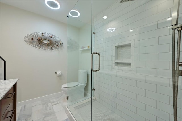 full bathroom featuring vanity, toilet, a shower stall, baseboards, and marble look tiles