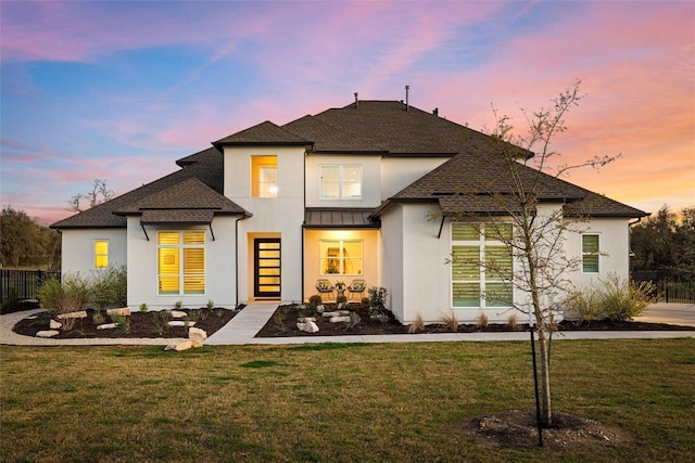 back of property with a lawn, stucco siding, and fence