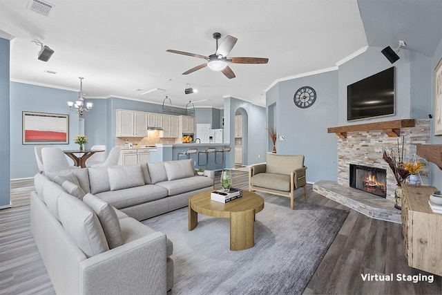 living room featuring wood finished floors, visible vents, ornamental molding, and ceiling fan with notable chandelier