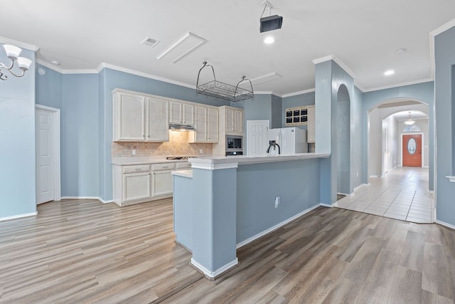 kitchen featuring appliances with stainless steel finishes, light wood-style floors, visible vents, under cabinet range hood, and arched walkways
