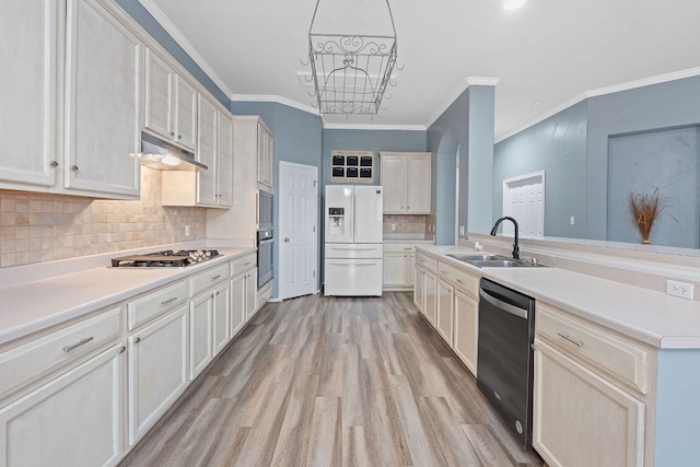 kitchen with light wood-style floors, under cabinet range hood, appliances with stainless steel finishes, a sink, and crown molding