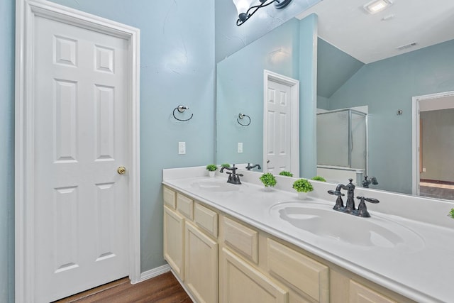 bathroom with vaulted ceiling, a stall shower, wood finished floors, and a sink