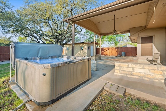 view of patio / terrace featuring an outbuilding, a ceiling fan, a hot tub, and fence