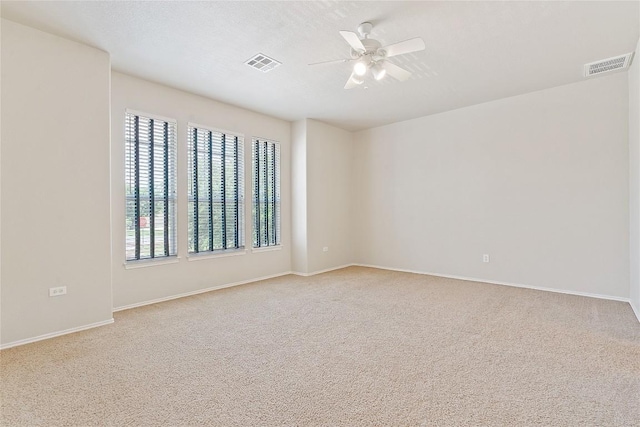 carpeted empty room with baseboards, ceiling fan, and visible vents