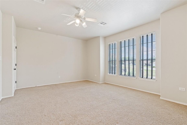 carpeted empty room with baseboards, visible vents, ceiling fan, and a textured ceiling