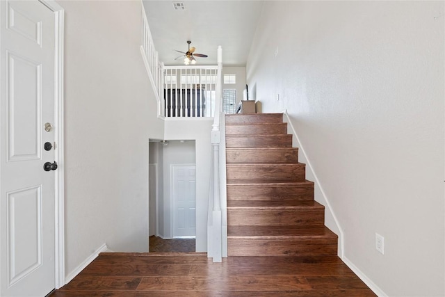 stairway with ceiling fan and wood finished floors