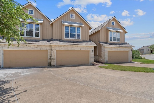 view of front facade featuring stone siding, board and batten siding, concrete driveway, and a garage