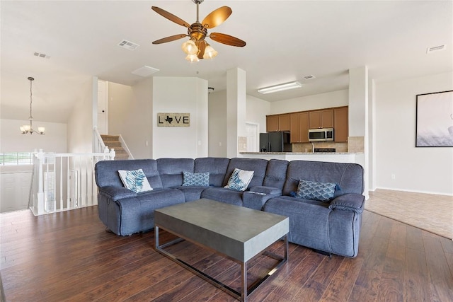 living room with ceiling fan with notable chandelier, visible vents, and dark wood-style flooring