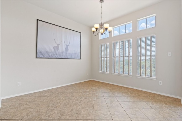 spare room with an inviting chandelier, light tile patterned flooring, and baseboards