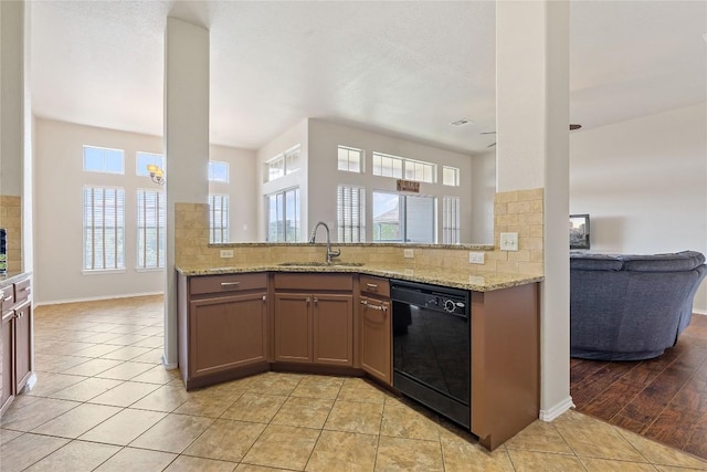 kitchen with a sink, tasteful backsplash, dishwasher, and light stone counters