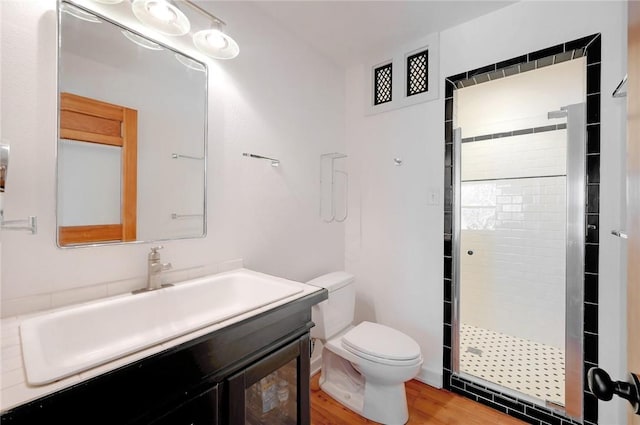 bathroom with wood finished floors, vanity, toilet, and a shower stall