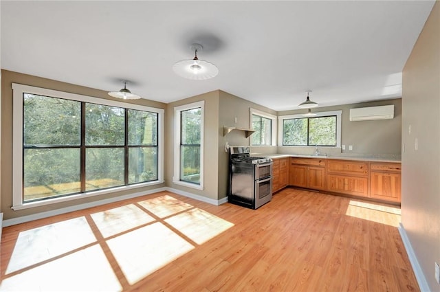 kitchen featuring double oven range, light wood-style floors, light countertops, an AC wall unit, and a sink