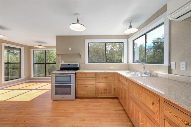kitchen with light wood-style flooring, a sink, light countertops, range with two ovens, and a wall mounted AC