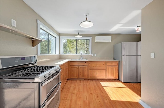 kitchen with a sink, light wood-style floors, light countertops, an AC wall unit, and appliances with stainless steel finishes