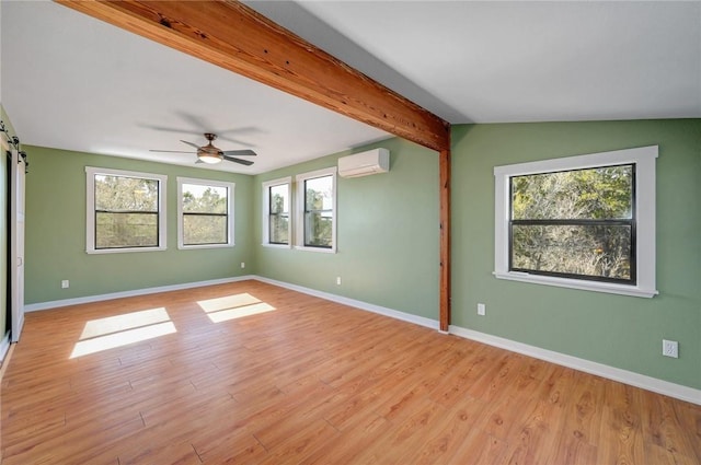 empty room with light wood-style flooring, a healthy amount of sunlight, and an AC wall unit