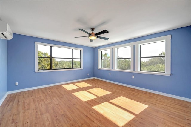 spare room featuring baseboards, a wall mounted air conditioner, ceiling fan, and light wood-style flooring