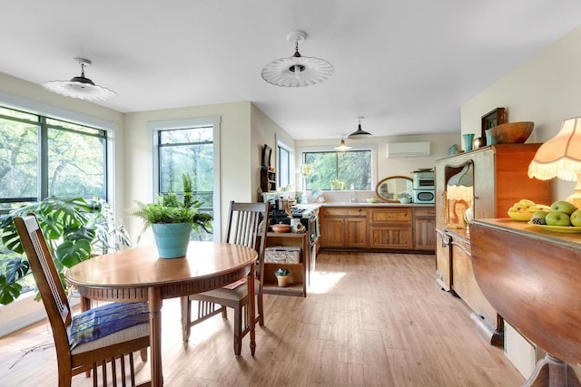 dining area with a wall mounted air conditioner and light wood finished floors