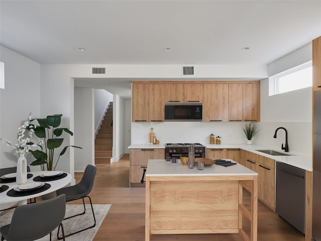 7516 Northcrest Blvd Unit B, Austin, TX 78752 - kitchen featuring black microwave, dishwasher, a sink, range with gas stovetop, and light wood-style floors
