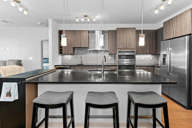 3600 S Lamar Blvd Unit 211, Austin, TX 78704 - kitchen featuring a sink, rail lighting, wall chimney exhaust hood, dark countertops, and appliances with stainless steel finishes