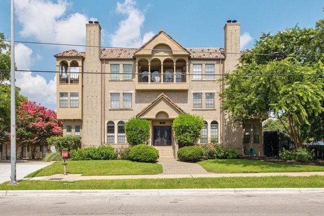 1704 W Ave Unit 108, Austin, TX 78701 - view of front of home with a chimney, a front lawn, stucco siding, and a balcony