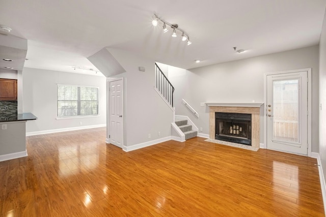 1704 W Ave Unit 108, Austin, TX 78701 - unfurnished living room with track lighting, light wood-style floors, stairs, and a fireplace with flush hearth