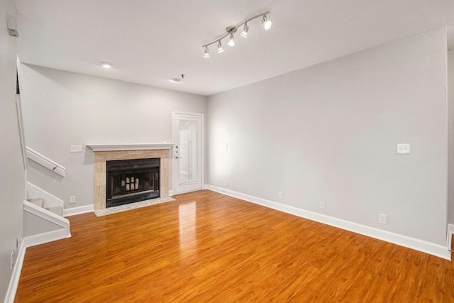 1704 W Ave Unit 108, Austin, TX 78701 - unfurnished living room featuring light wood-style floors, a tile fireplace, and baseboards