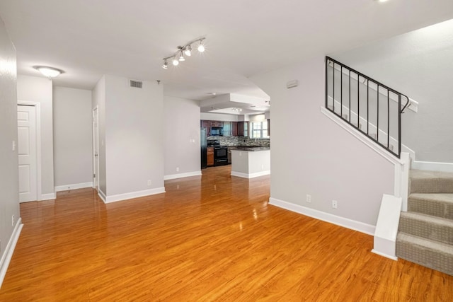 1704 W Ave Unit 108, Austin, TX 78701 - unfurnished living room featuring stairway, light wood-style flooring, and baseboards
