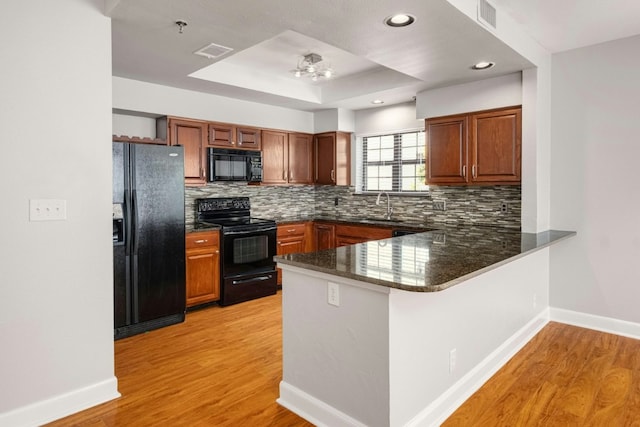 1704 W Ave Unit 108, Austin, TX 78701 - kitchen with black appliances, a sink, a peninsula, baseboards, and recessed lighting