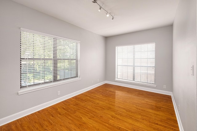 1704 W Ave Unit 108, Austin, TX 78701 - unfurnished room with rail lighting, baseboards, and wood finished floors