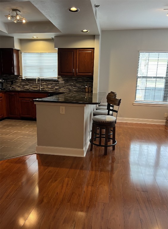 1704 W Ave Unit 108, Austin, TX 78701 - kitchen with dark countertops, a breakfast bar area, plenty of natural light, and tasteful backsplash