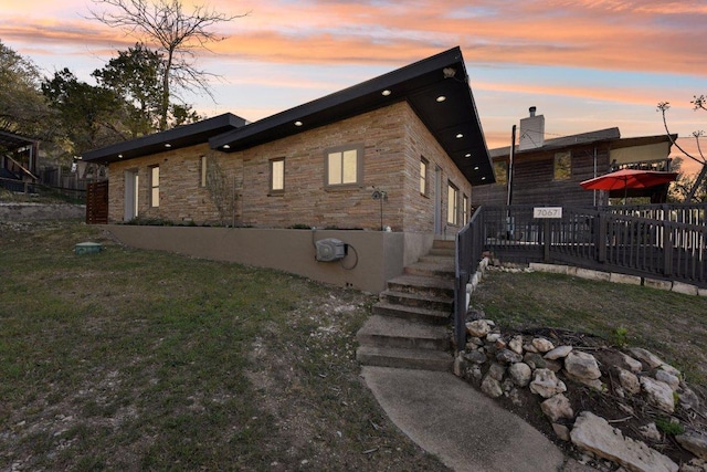 7067 Comanche Trl, Austin, TX 78732 - view of side of property featuring stone siding, a deck, and a yard