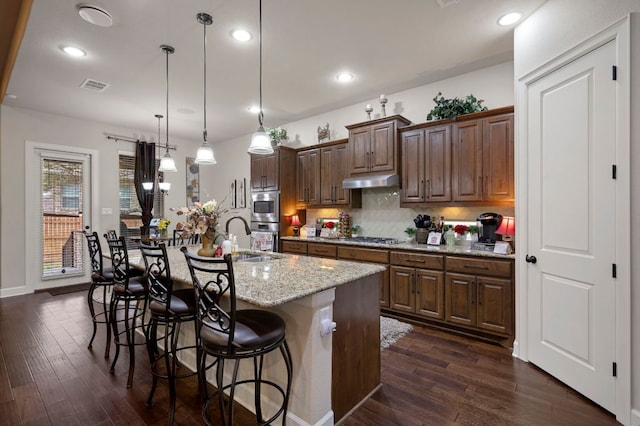 2429 Carretera Dr, Leander, TX 78641 - kitchen featuring a sink, dark wood-style floors, a kitchen bar, backsplash, and a kitchen island with sink