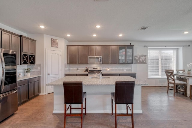 4108 Gildas Path, Pflugerville, TX 78660 - kitchen featuring stainless steel appliances, tasteful backsplash, wood finished floors, recessed lighting, and a textured ceiling