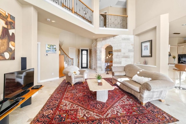 329 Park Place Dr, Georgetown, TX 78628 - tiled living area featuring a towering ceiling, stairway, arched walkways, and baseboards