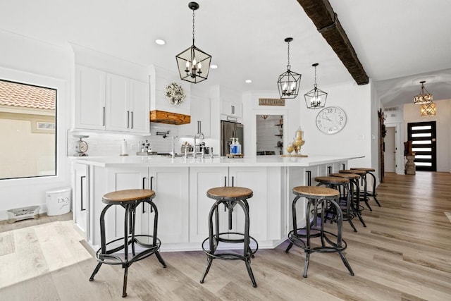 kitchen featuring a chandelier, light wood finished floors, a breakfast bar, and stainless steel fridge
