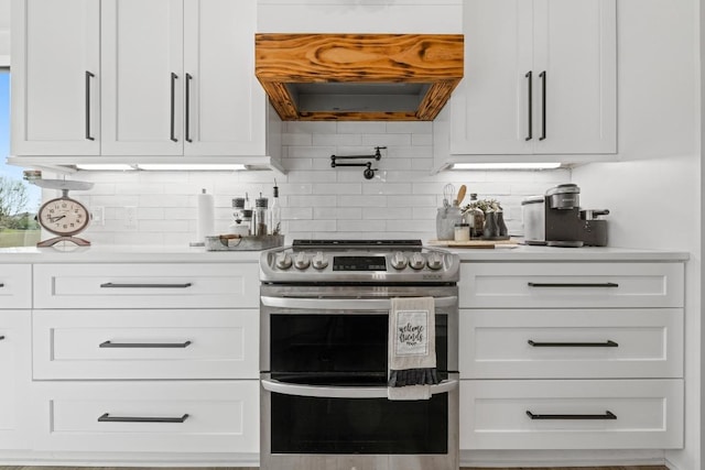 kitchen with light countertops, range with two ovens, white cabinetry, and premium range hood