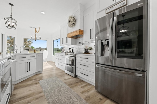 kitchen featuring tasteful backsplash, a notable chandelier, white cabinets, appliances with stainless steel finishes, and pendant lighting