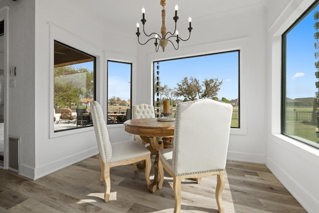 dining area with light wood-type flooring, a notable chandelier, and baseboards